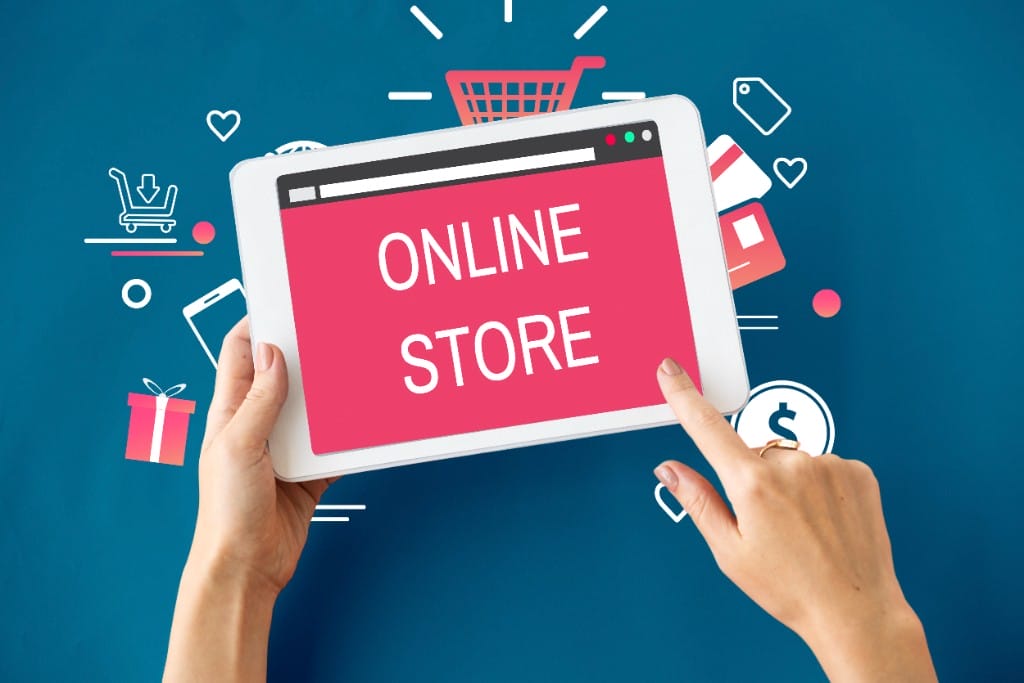 Hands holding a tablet displaying an ONLINE STORE screen surrounded by shopping cart and payment icons